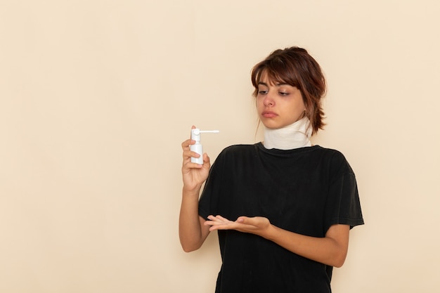 Vorderansicht kranke junge Frau, die sich krank fühlt und Spray für Hals auf hellweißer Oberfläche verwendet