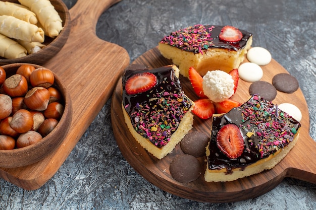 Vorderansicht-Kuchenscheiben mit Nüssen und Süßigkeiten auf dunklem Hintergrund