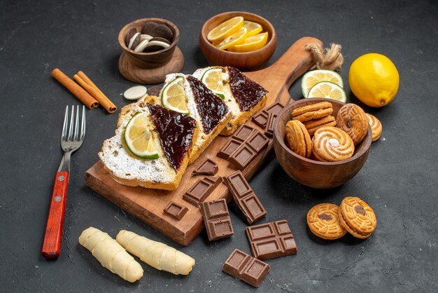 Vorderansicht-Kuchenscheiben mit Schokolade und Keksen auf dunklem Hintergrund