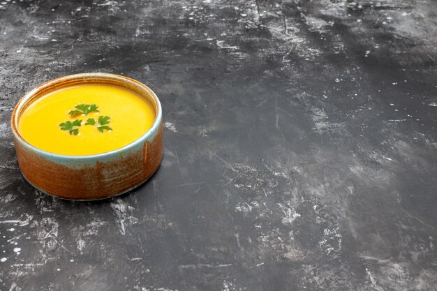 Vorderansicht-Kürbissuppe mit Grün innerhalb Platte auf einem dunklen Tisch