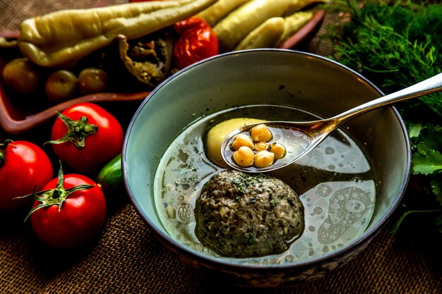 Vorderansicht Kufta-Bozbash-Suppe traditionelle aserbaidschanische Suppe, serviert mit Tomaten und gesalzenem Gemüse