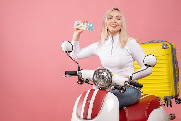 Vorderansicht lächelnde junge Dame auf Moped zeigt Ticket