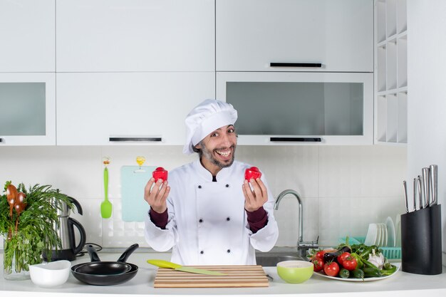 Vorderansicht lächelnder männlicher Koch in Uniform, der Salzstreuer in der Küche hält