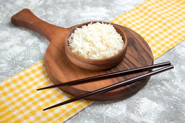 Vorderansicht lecker gekochter Reis in brauner Platte auf weißem Raum
