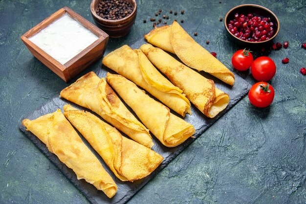 Vorderansicht lecker gerollte Pfannkuchen mit Tomaten auf dunkler Oberfläche ausgekleidet