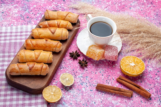 Vorderansicht leckere bagels mit zimt und tasse tee auf rosa schreibtisch.