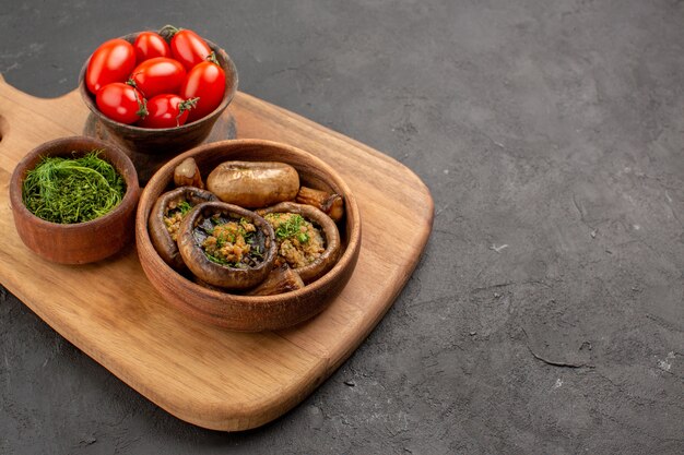 Vorderansicht leckere gekochte Pilze mit Tomaten auf dunklem Tisch reifes wildes Essen