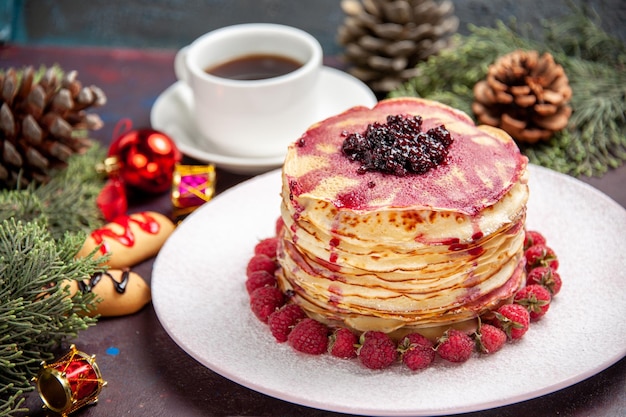 Vorderansicht leckere Geleepfannkuchen mit Erdbeeren und Tasse Tee auf dunklem Raum