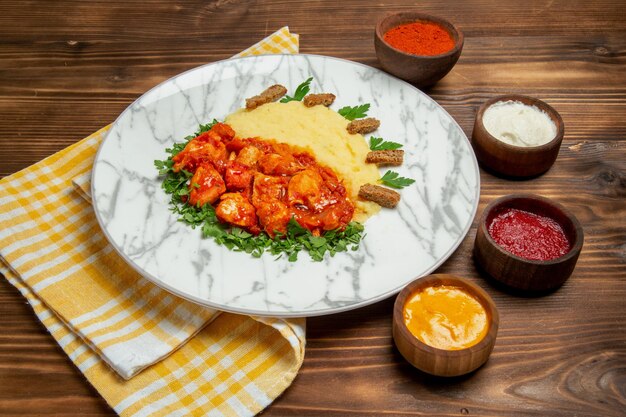 Vorderansicht leckere Hähnchenscheiben mit Kartoffelpüree und Gewürzen auf braunem Schreibtisch Fleischgericht Abendessen Kartoffelmahlzeit