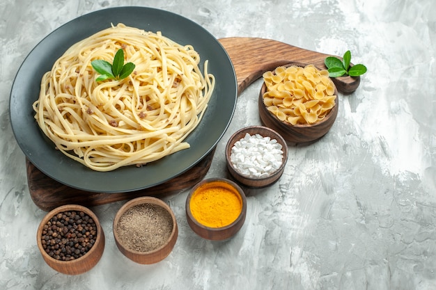 Vorderansicht leckere italienische Pasta mit Gewürzen auf hellem Teig Farbe Foto Essen Gericht