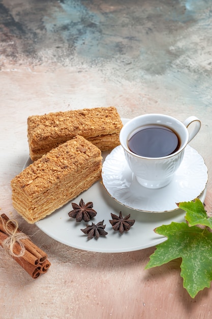 Vorderansicht leckere Kuchenscheiben mit einer Tasse Tee auf Licht