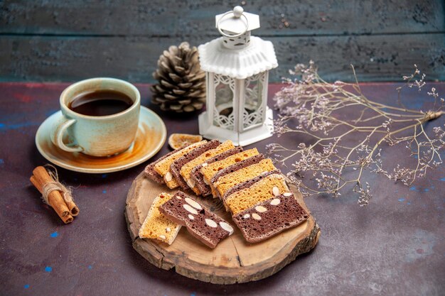 Kostenloses Foto vorderansicht leckere kuchenscheiben mit nüssen und tasse tee auf dunklem raum