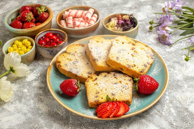 Vorderansicht leckere Kuchenstücke mit Erdbeeren auf süßen süßen Tortenkuchen mit leichten Oberflächenfrüchten