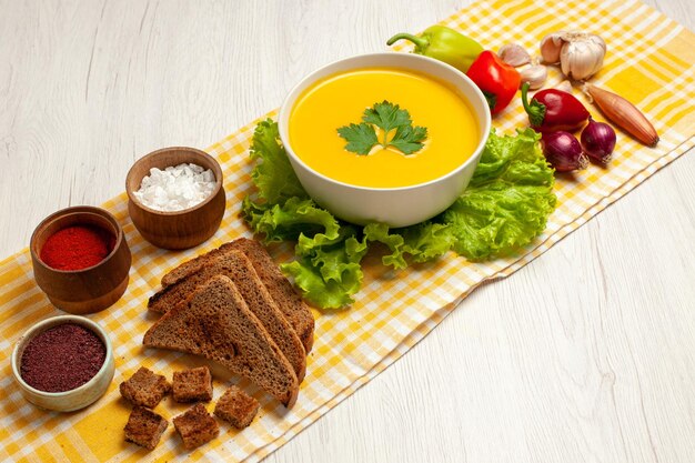 Vorderansicht leckere Kürbissuppe mit verschiedenen Gewürzen und Brot auf weißem Raum