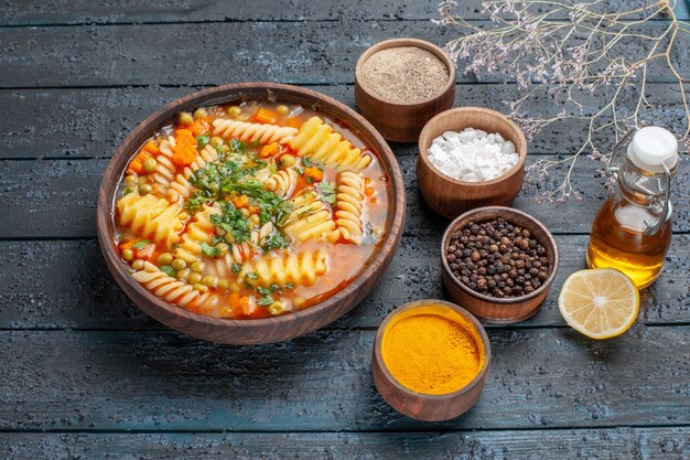 Vorderansicht leckere Nudelsuppe aus Spiralnudeln mit Gewürzen auf dunkelblauer Schreibtischsauce Küche Gericht italienische Nudelsuppe