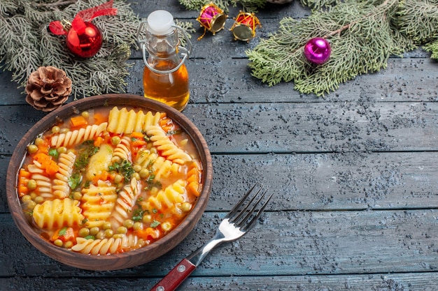 Vorderansicht leckere Pastasuppe aus spiralförmiger italienischer Pasta mit Grüns auf dunkelblauer Schreibtischküche Pastasuppe Gericht Abendessen Farbe