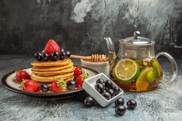 Vorderansicht leckere Pfannkuchen mit frischen Früchten auf süßem Obstkuchen der leichten Oberfläche