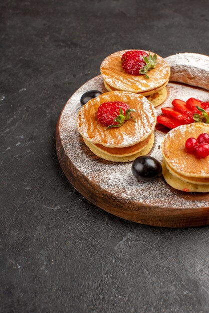 Vorderansicht leckere Pfannkuchen mit Früchten und Kuchen auf der dunklen Oberfläche Frucht süßer Kuchen