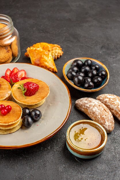 Vorderansicht leckere Pfannkuchen mit Früchten und Kuchen auf dunklem Obstkuchen der dunklen Oberfläche