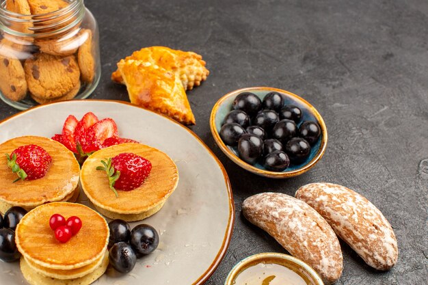 Vorderansicht leckere Pfannkuchen mit Früchten und Kuchen auf dunklem Obstkuchen der dunklen Oberfläche