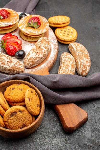 Vorderansicht leckere Pfannkuchen mit Früchten und süßen Kuchen auf dunklem Oberflächenkuchen-Nachtisch süß