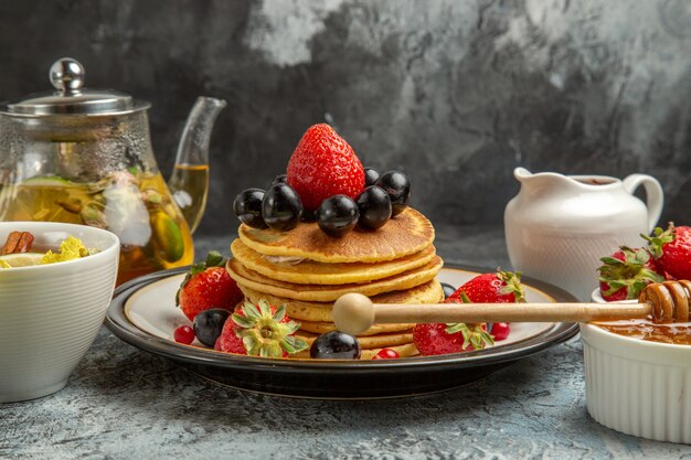 Vorderansicht leckere Pfannkuchen mit Früchten und Tee auf leichtem süßem Fruchtfrühstück der Oberfläche