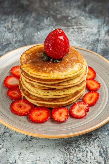 Vorderansicht leckere Pfannkuchen mit Honig und Erdbeeren auf der leichten Oberfläche Kuchenfrucht süß