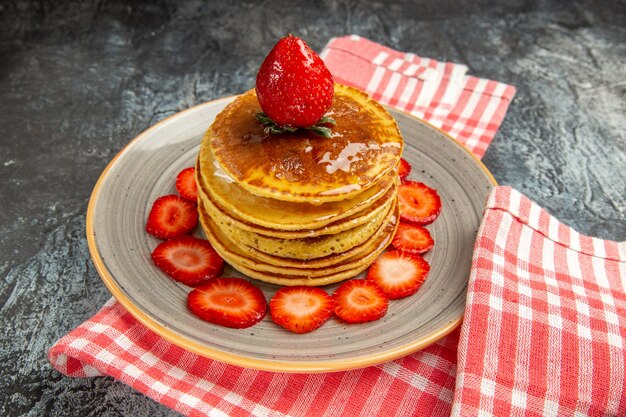 Vorderansicht leckere Pfannkuchen mit Honig und Früchten auf leichtem milchsüßem Obstkuchen