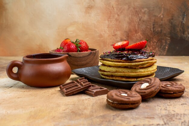 Vorderansicht leckere Pfannkuchen mit Keksen und Früchten auf Holzschreibtisch