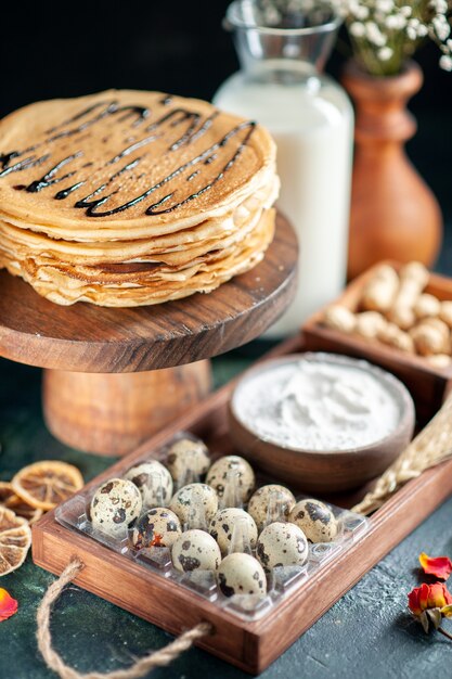 Vorderansicht leckere Pfannkuchen mit Nüssen und Milch auf dunkelblauer Oberfläche