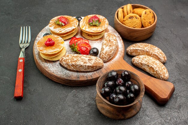 Vorderansicht leckere Pfannkuchen mit süßen Kuchen und Früchten auf dunkler Oberfläche Kuchen Dessert süß