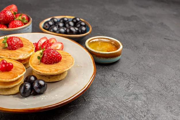 Kostenloses Foto vorderansicht leckere pfannkuchen wenig gebildet mit früchten auf einer grauen oberfläche tortenkuchenfrucht