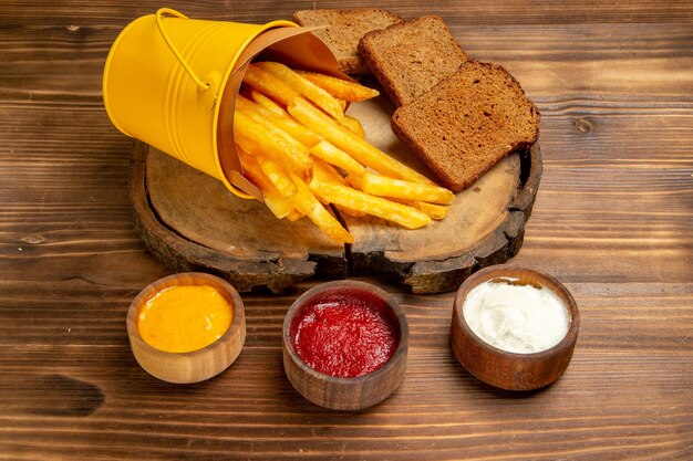 Vorderansicht leckere Pommes frites mit Gewürzen auf brauner Kartoffel-Fast-Food-Brotmahlzeit