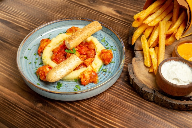 Vorderansicht leckere Pommes frites mit Gewürzen und Hühnchen auf braunem Schreibtisch Kartoffel-Mittagessen Fast-Food-Mahlzeit Brot