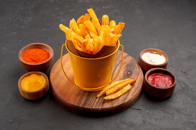 Vorderansicht leckere Pommes frites mit Saucen auf dunklem Raum