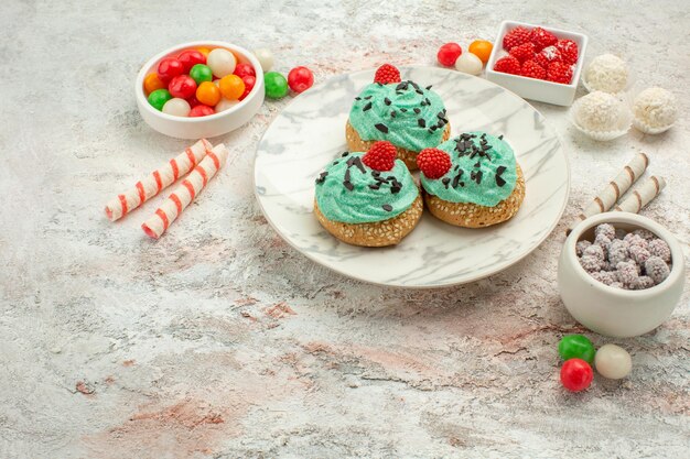 Vorderansicht leckere Sahnetorten mit bunten Bonbons auf weißem Hintergrund Kuchen Keks süße Dessertcreme