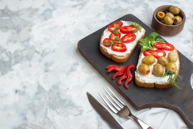 Vorderansicht leckere Sandwiches mit Paprika und Oliven auf Schneidebrett weißer Hintergrund Mittagessen Sandwich Essen Burger Brot Toast