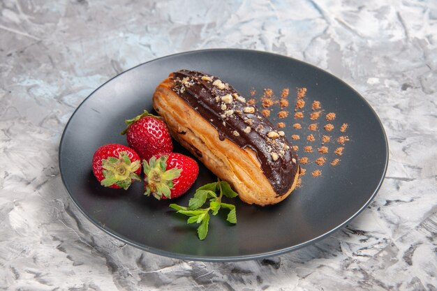 Vorderansicht leckere Schoko-Eclairs mit Erdbeeren auf dem Leuchttisch Dessert Kuchen Süßigkeiten