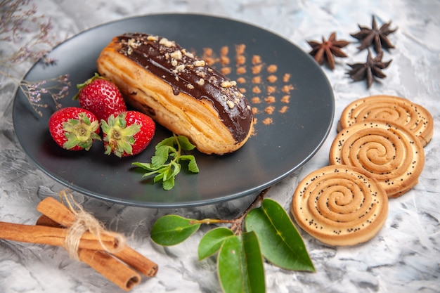 Vorderansicht, leckere Schoko-Eclairs mit Keksen auf Leuchttisch-Keks-Kuchen-Dessert