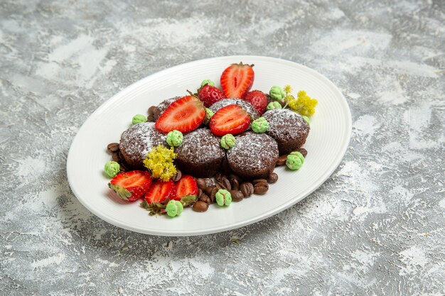 Vorderansicht leckere Schokoladenkuchen mit frischen Erdbeeren und Schokoladenstückchen auf weißer Oberfläche Keks Schokolade süße Kuchen backen Kekse