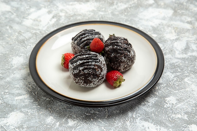 Vorderansicht leckere schokoladenkuchen mit frischen roten erdbeeren auf weißer oberfläche backen kekszuckerkuchen süße keksschokolade