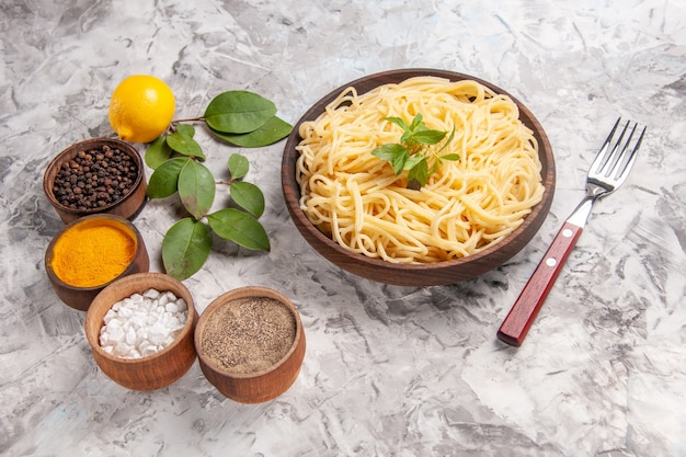 Vorderansicht leckere spaghetti mit gewürzen auf weißem schreibtisch teig mahlzeit nudelgericht
