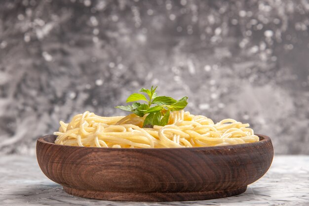Vorderansicht leckere Spaghetti mit grünem Blatt auf hellweißen Tischgerichten Teignudeln