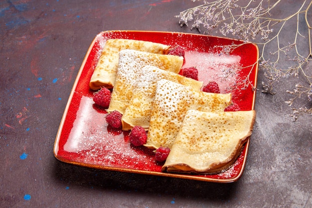 Vorderansicht leckere süße Pfannkuchen in rotem Teller mit Himbeeren auf dunklem Raum