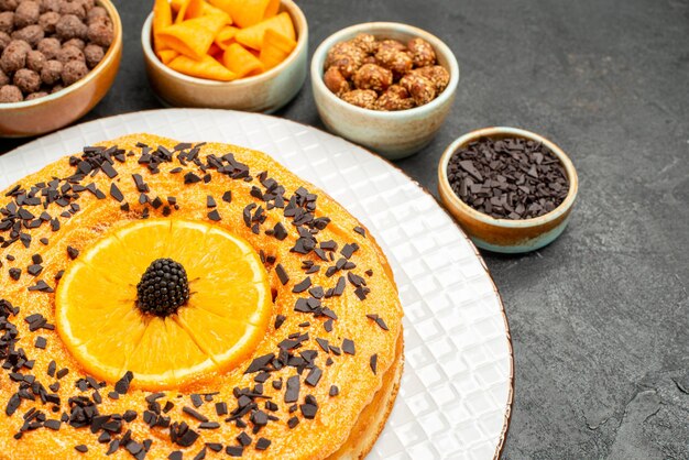 Vorderansicht leckere süße Torte mit Orangenscheiben auf grauem Schreibtisch Tortenkeks Dessert süßer Kuchentee