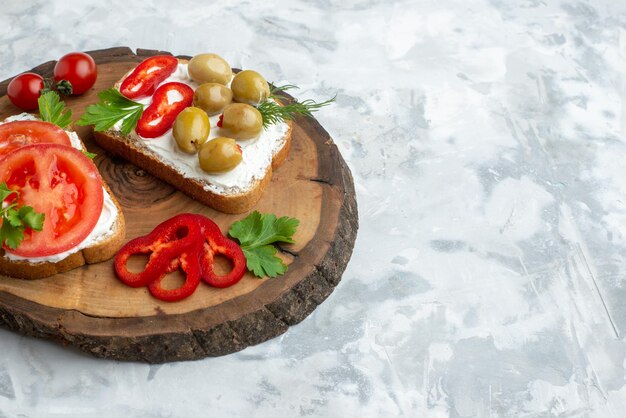 Vorderansicht leckere Toasts mit Tomaten und Oliven auf Holzbrett weißer Hintergrund Burger Abendessen Brot Mahlzeit horizontales Sandwich Essen