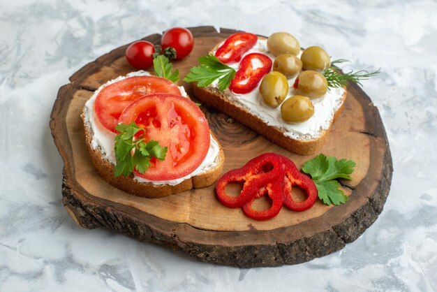 Vorderansicht leckere Toasts mit Tomaten und Oliven auf Holzbrett weißer Hintergrund Burgerbrot Mahlzeit horizontales Essen Abendessen Mittagessen Sandwich