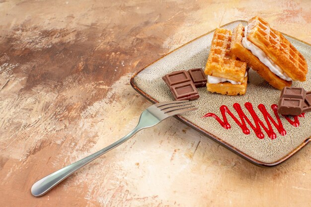 Vorderansicht leckere Waffelkuchen mit Schokoriegeln auf dem braunen Hintergrund