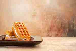 Kostenloses Foto vorderansicht leckere waffelkuchen mit schokoriegeln auf dem braunen hintergrund