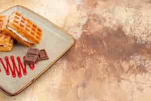 Kostenloses Foto vorderansicht leckere waffelkuchen mit schokoriegeln auf dem braunen hintergrund